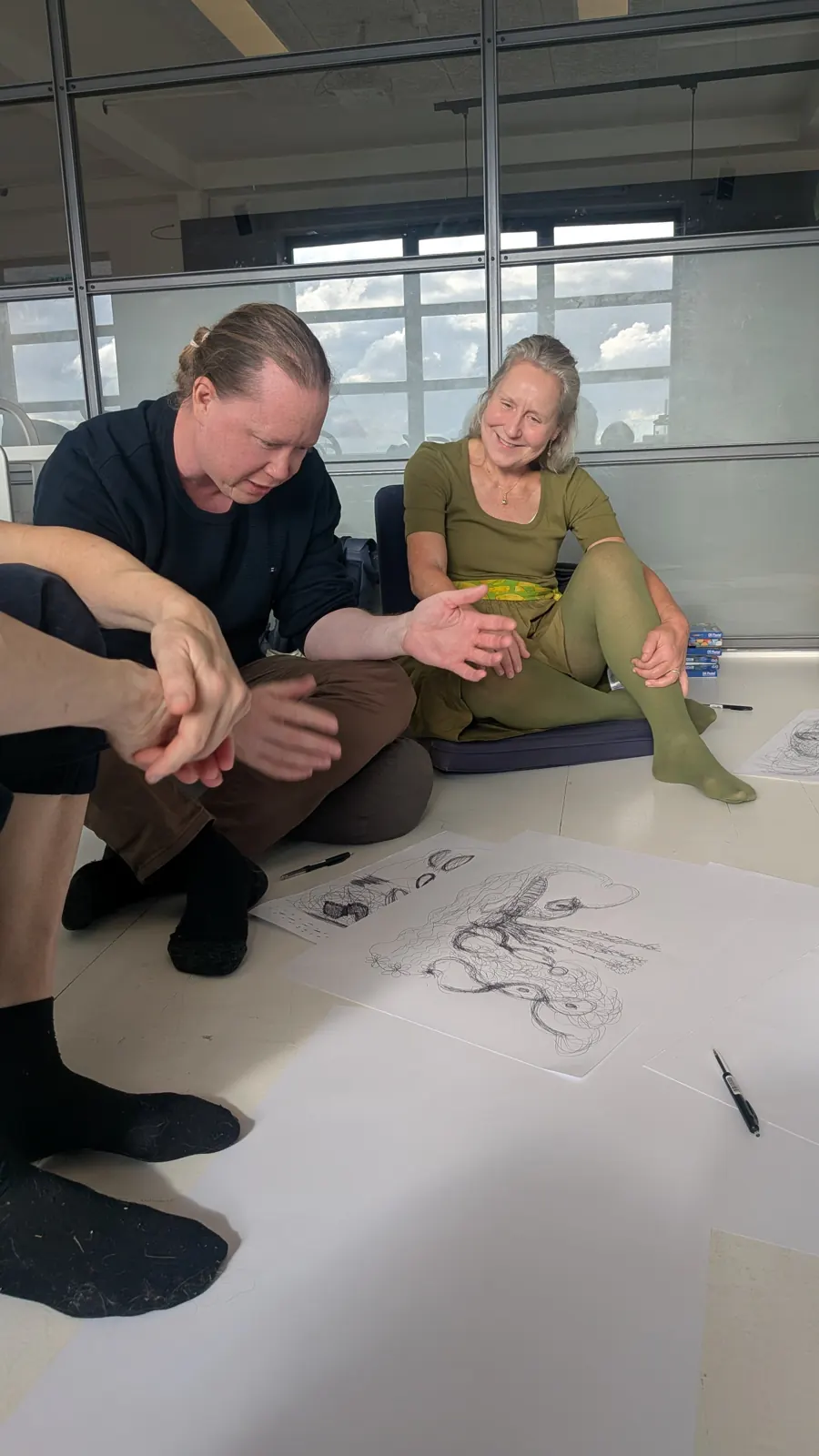 Deltagere tegner sammen på gulvet under en workshop